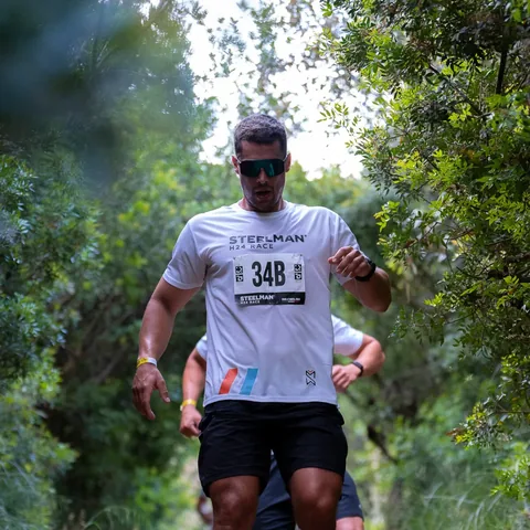 A runner in a Steelman vest on a wooded coastal trail.