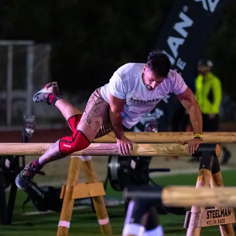 An athlete vaulting a wooden beam at the venue.